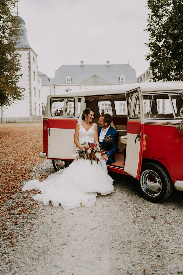 Les mariés assis dans le combi Volkswagen rouge, mariage à Deulin