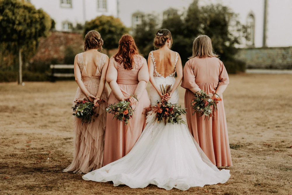 La mariée et ses demoiselles d'honneur de dos face au château, mariage à Deulin