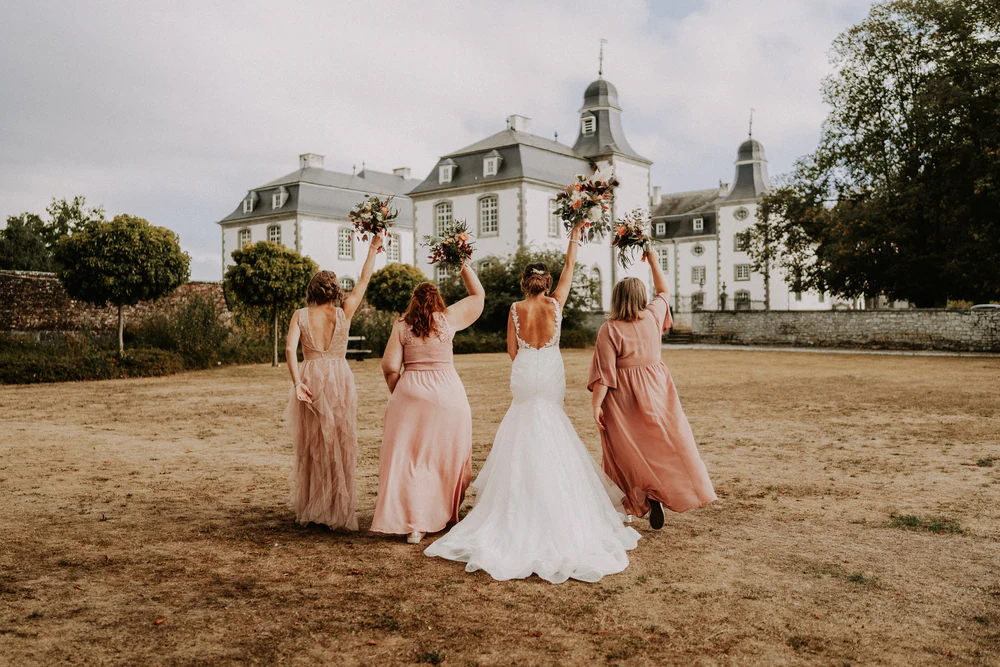 Les demoiselles d'honneur lèvent leurs bouquets devant le Château de Deulin
