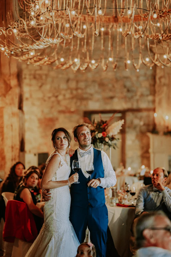 Les mariés posent devant leurs invités dans la grange, mariage à Deulin