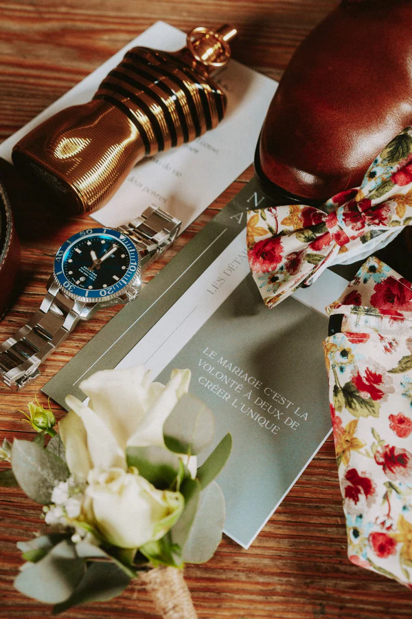 Préparatifs du marié : parfum, montre, chaussures, nœud papillon fleuri et boutonnière, mariage au Primordia