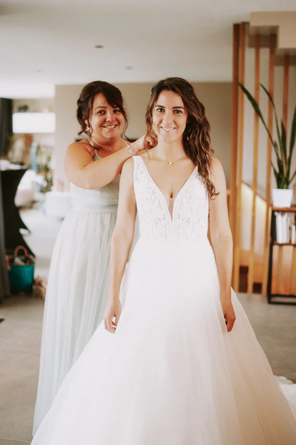 La mariée aidée pour enfiler sa robe, préparatifs du mariage au Primordia