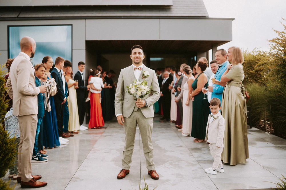 Le marié attend la mariée devant la haie d'honneur des invités, mariage au Primordia