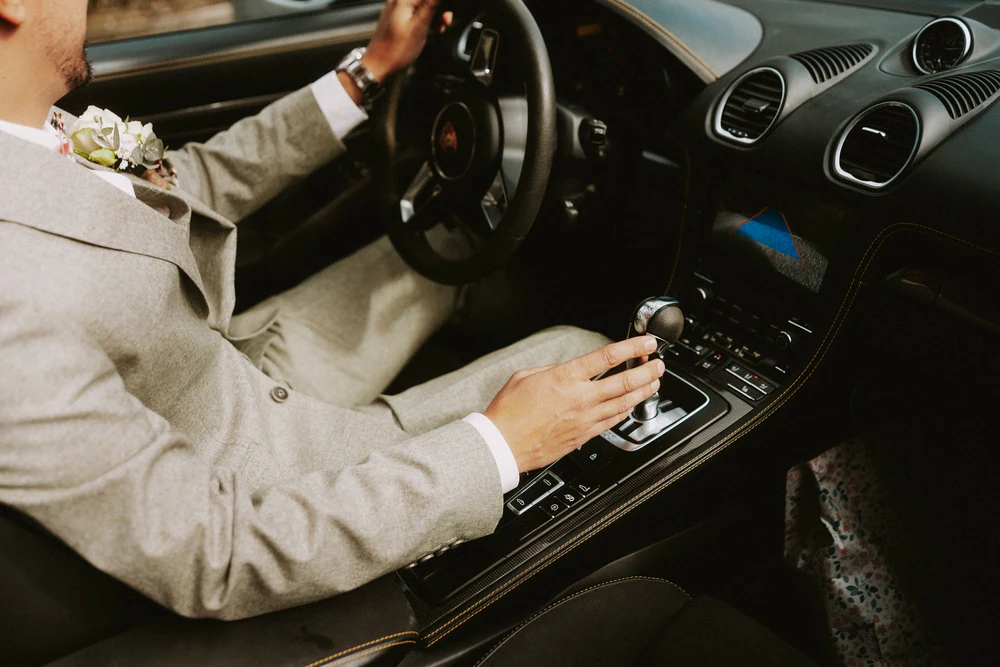 La main du marié sur le levier de vitesse du cabriolet, mariage au Primordia