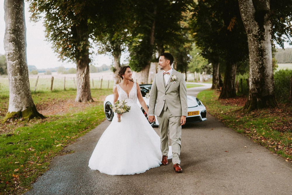 Les mariés marchent sur l'allée bordée de grands arbres, mariage au Primordia