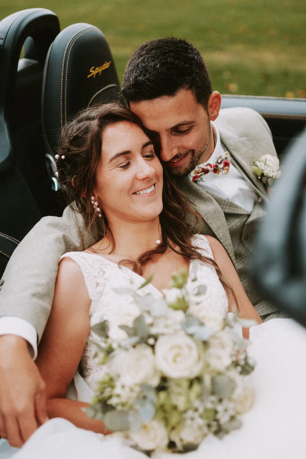 Les mariés blottis dans le cabriolet blanc, mariage au Primordia