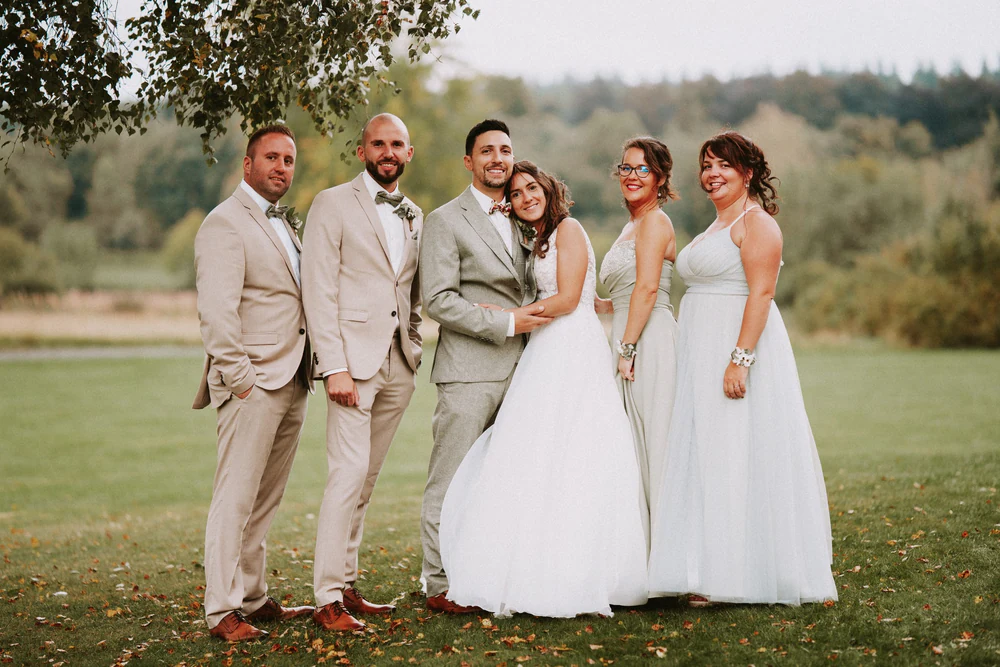 Photo de groupe des témoins autour des mariés sur la pelouse, mariage au Primordia