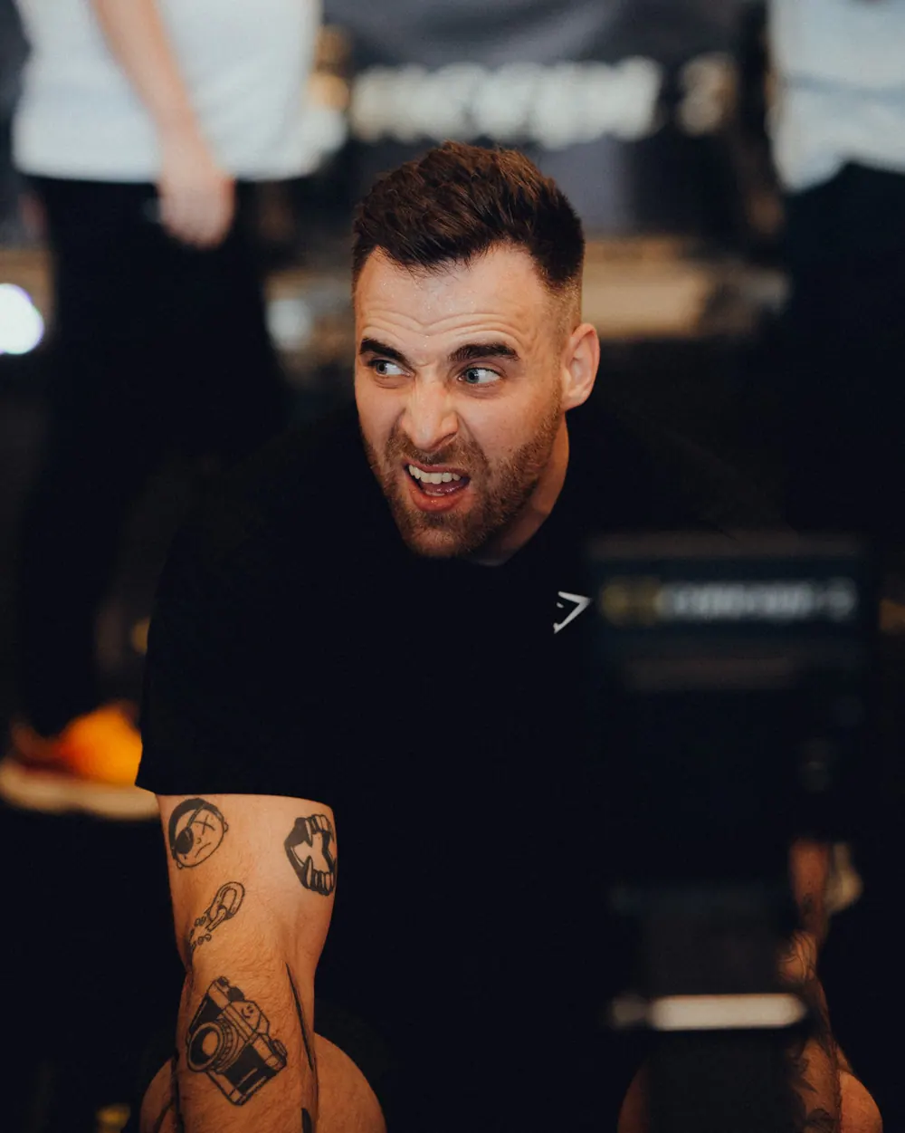 Gautier Collet faisant une grimace, son tatouage d'appareil photo sur l'avant-bras